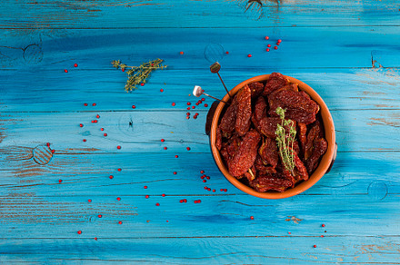 Mediterranean dried tomatoes inside a bowl on blue rustic wooden, a Food & Drink Photo by Bepslabor