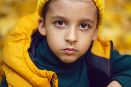 portrait of a fashionable serious child boy autumn sitting on a trail in orange, a Person Photo by SaulichPhoto