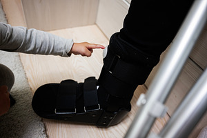 Child pointing at a medical orthopedic boot with crutch nearby, a Health & Medical Photo by AS photostudio