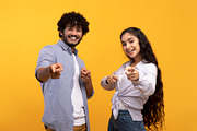And what's about you. Excited indian couple pointing index fingers at camera, p, a Photo by Prostock-Studio (Thumbnail 2 of 4)