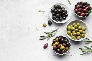 Assorted olives in decorative bowls on white surface, a Food & Drink Photo by Olena Rudo