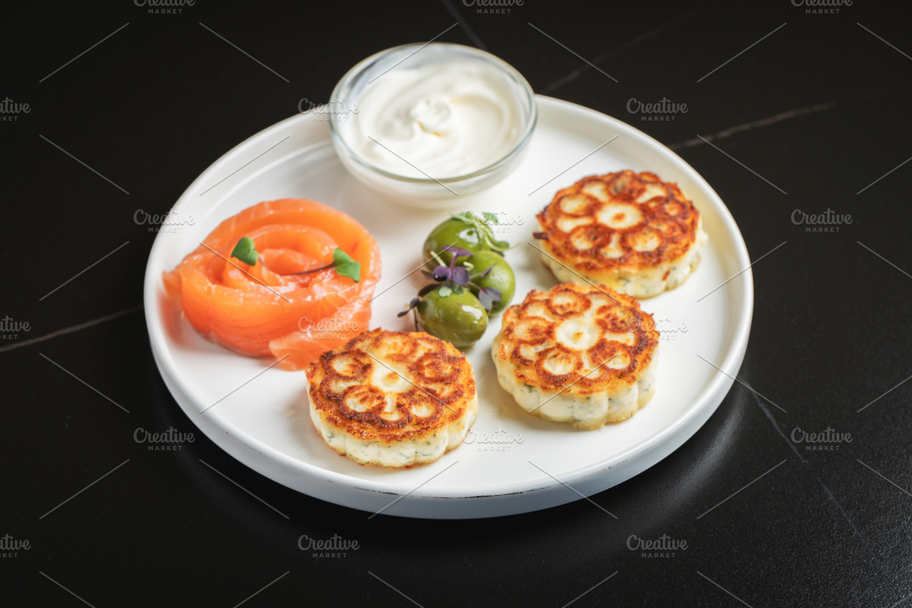 Savory Syrniki with Smoked Salmon, Olives and Sour Cream on White Plate, a Food & Drink Photo by Budarinphoto