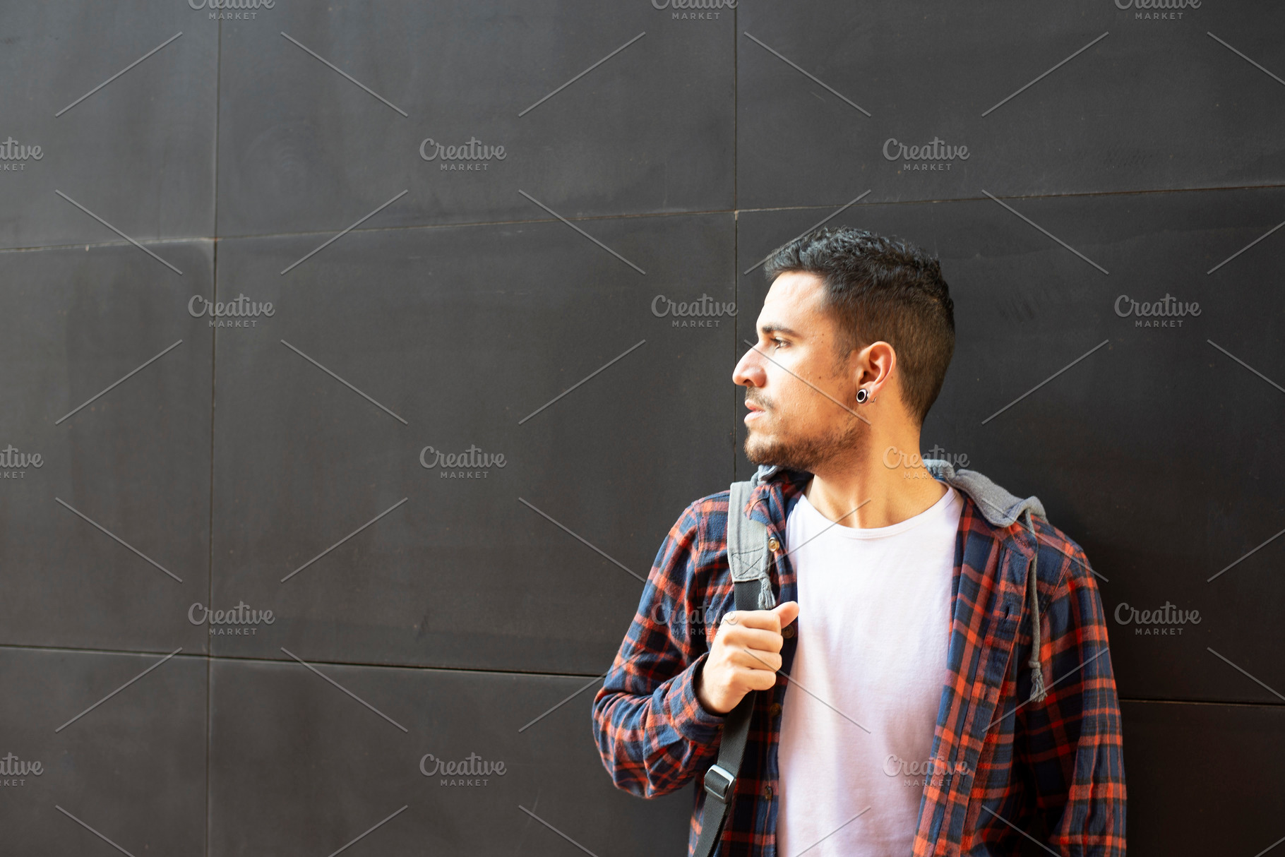 Caucasian man with backpack standing against dark wall, a Person Photo by RF Images