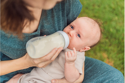 Mother holding and feeding baby from, a Person Photo by Elizaveta Galitskaya
