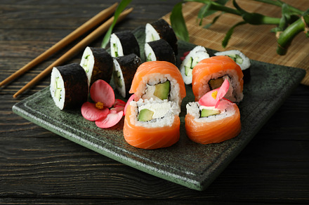 Concept of tasty food with sushi rolls on wooden background, a Food & Drink Photo by AtlasStudio