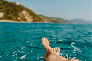 Woman relaxing on beach by sea, feet, a Nature Photo by HalfPoint