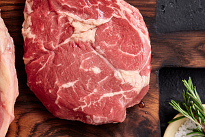 Raw rib-eye steak and other cuts placed on a wooden board with seasoning in a k, a Food & Drink Photo by Asya Nurullina