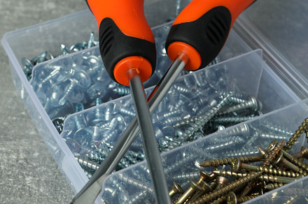 Box with screws and screwdrivers on gray textured background, an Industrial Photo by AtlasStudio PRO