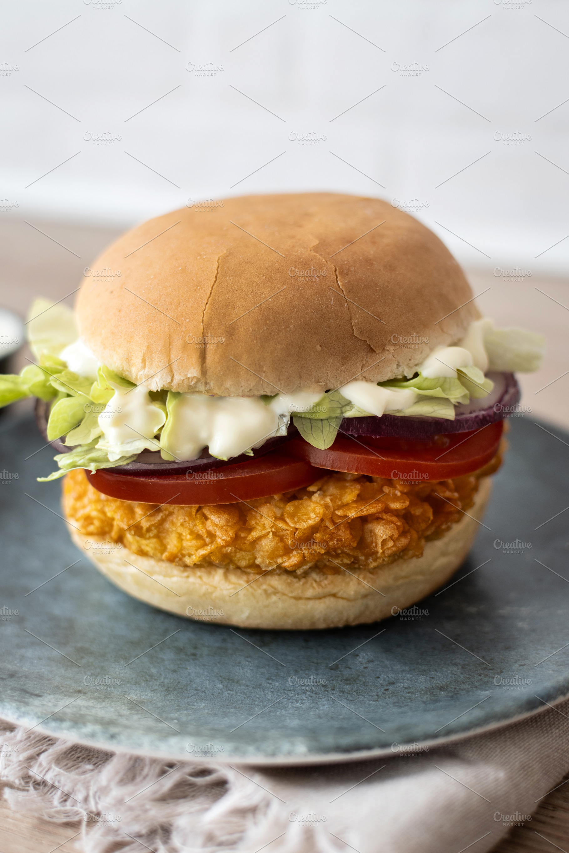 Crispy chicken burger on plate with lettuce tomato and sauce, a Food & Drink Photo by etorres69