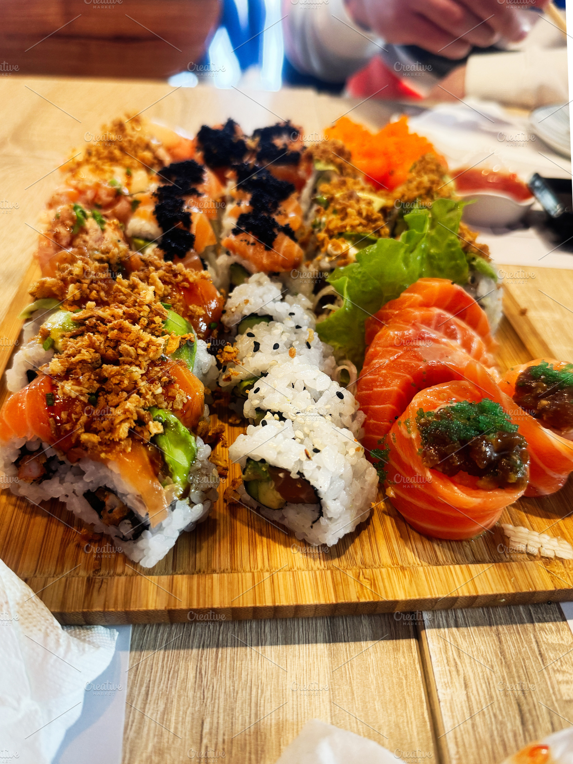 Assorted sushi rolls and fresh sashimi served on a wooden platter in a restaura, a Photo by AS photostudio
