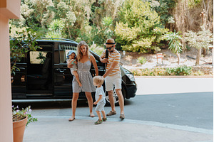 Parents with toddlers boarding car, a Transportation Photo by HalfPoint