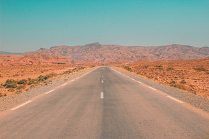 Road in the desert with mountains, a Nature Photo by The Pixels Factory