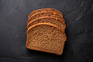 Sliced baked rye bread on black background, a Food & Drink Photo by AlyaAnd
