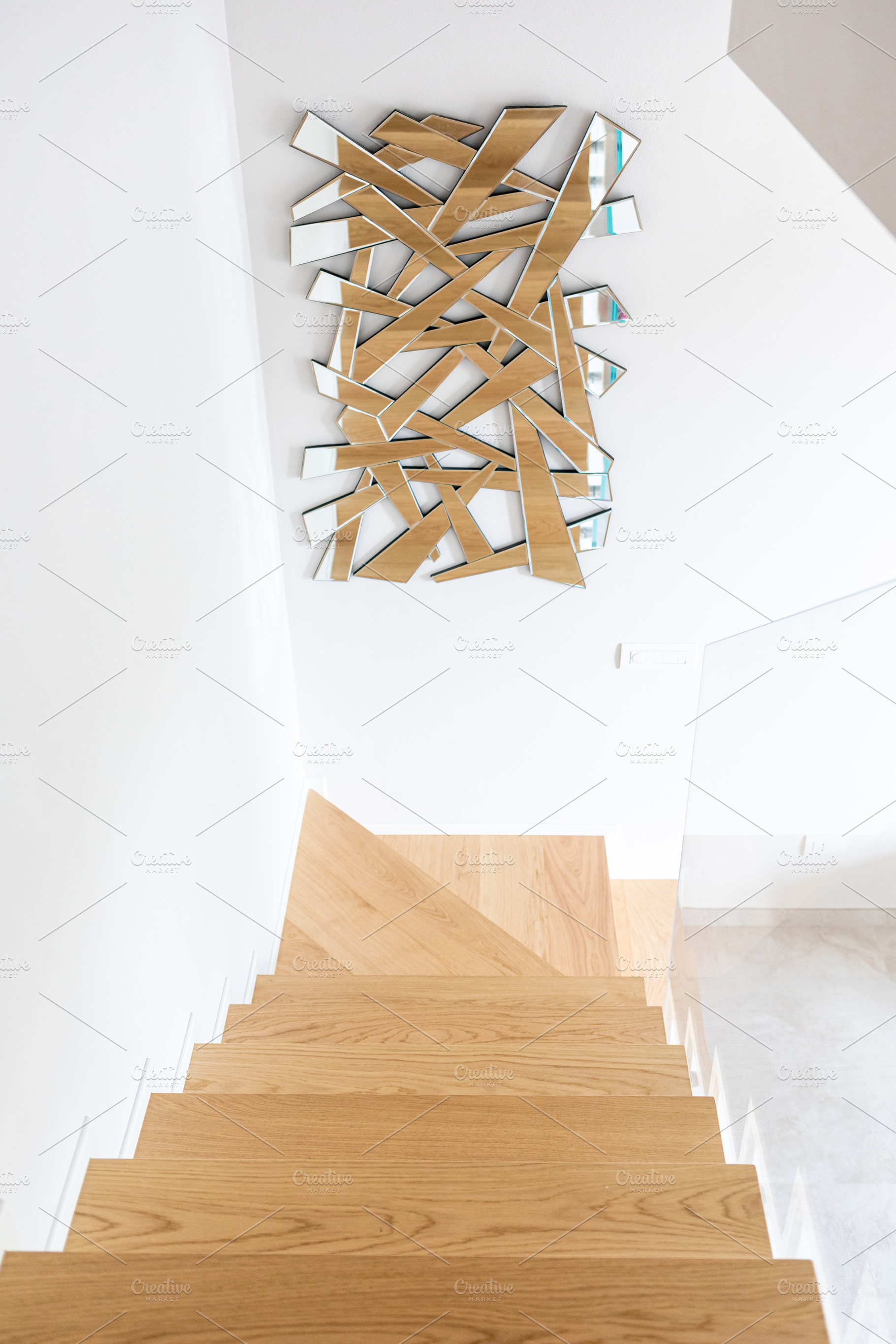 Modern wooden staircase with abstract mirror on white wall, an Architecture Photo by Antonio Gravante Market