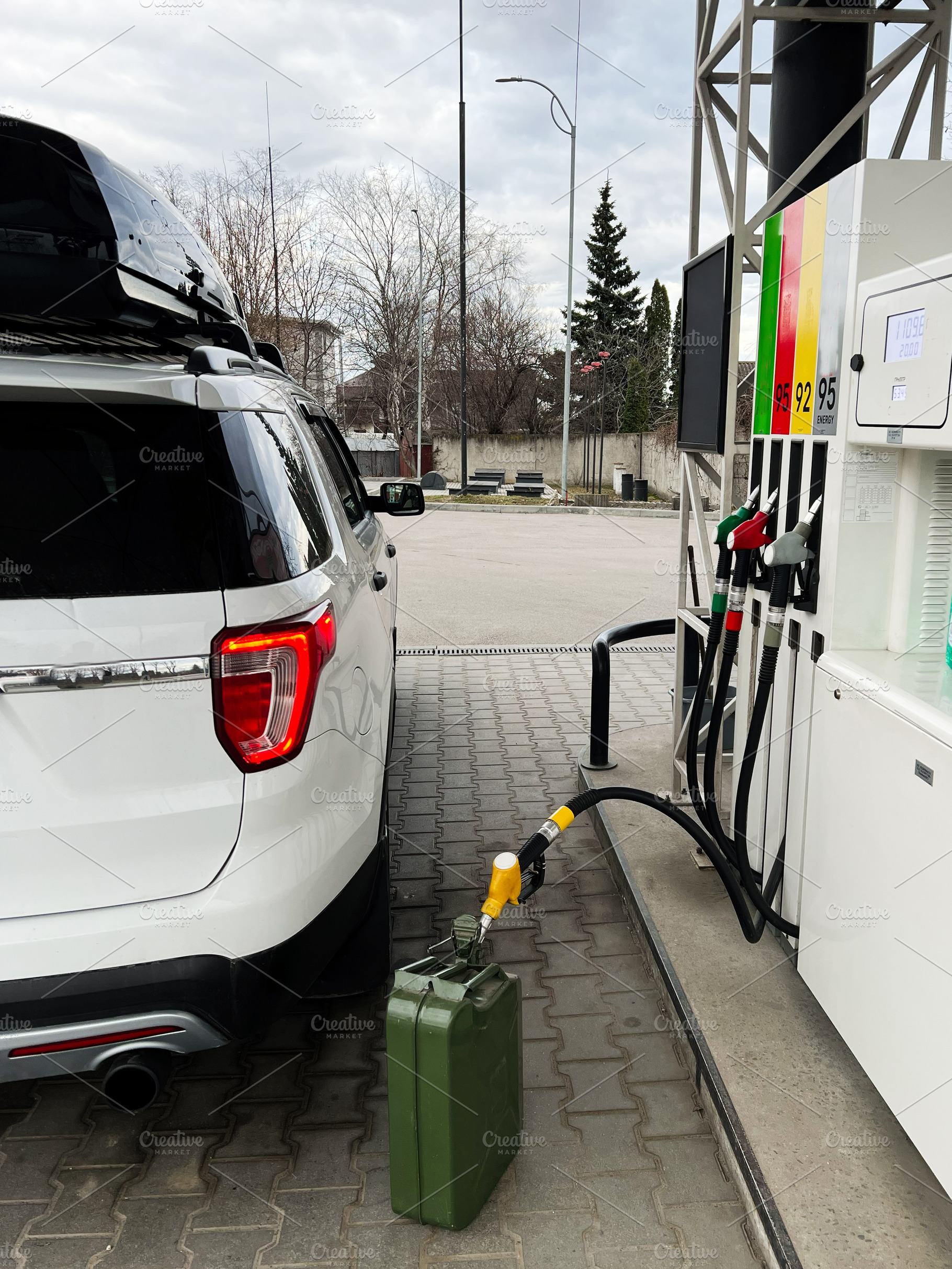 White SUV Refueling at a Gas Station with a Green Fuel Can, a Photo by AS photostudio