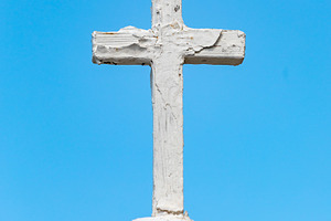 White wooden cross standing on a weathered dome against blue sky, a Photo by Antonio Gravante Market