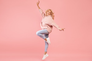 Playful caucasian woman jumping and having fun over pink studio background, lad, a Photo by Prostock-Studio
