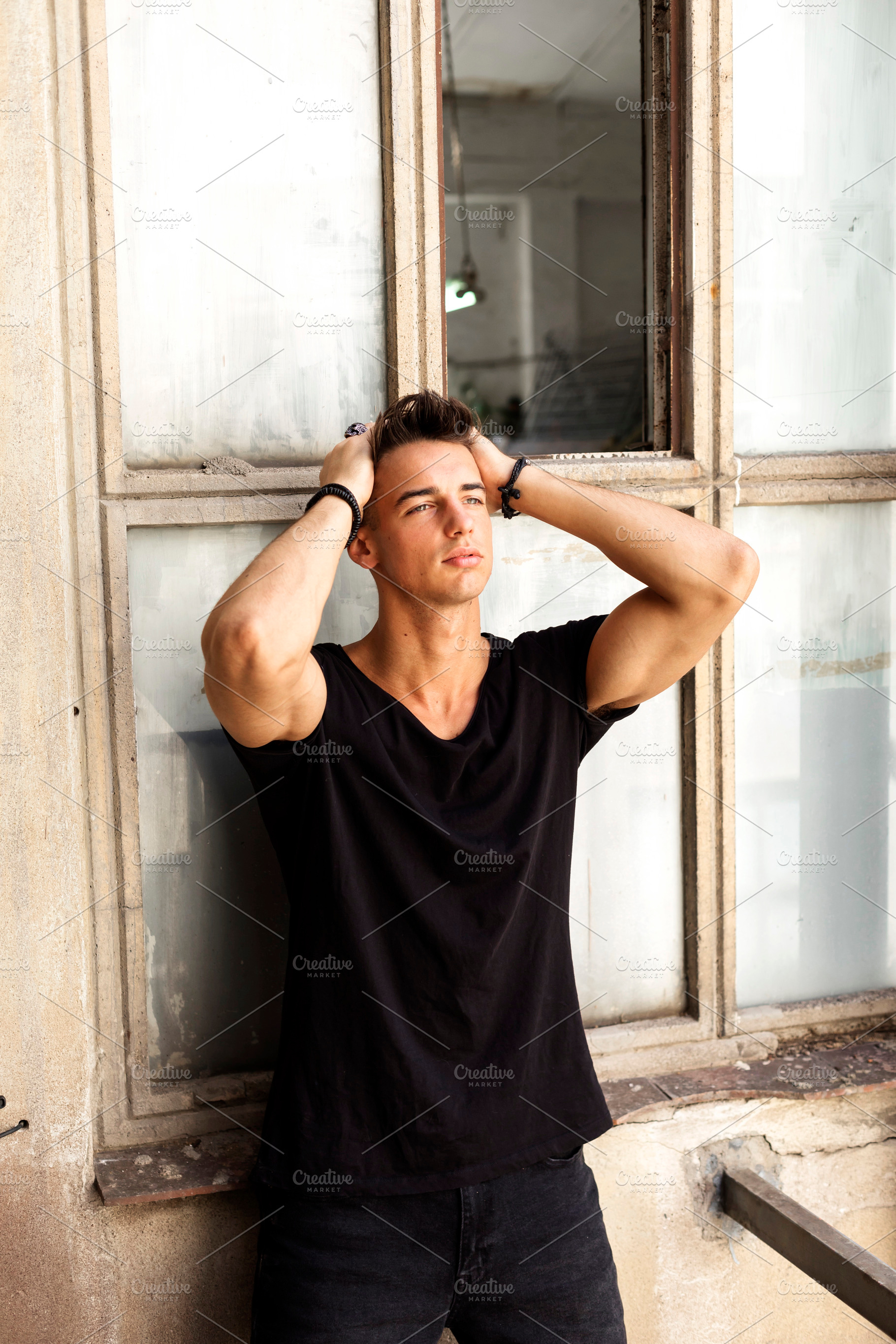 Young man posing with hands in hair by window, a Person Photo by RF Images
