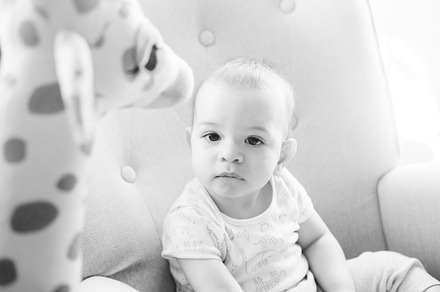Portrait of a nine month old baby with a stuffed giraffe sitting in a rocking c