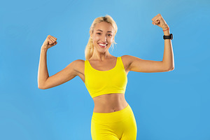 Happy sporty woman showing strong biceps muscles at studio, a Photo by Prostock-Studio