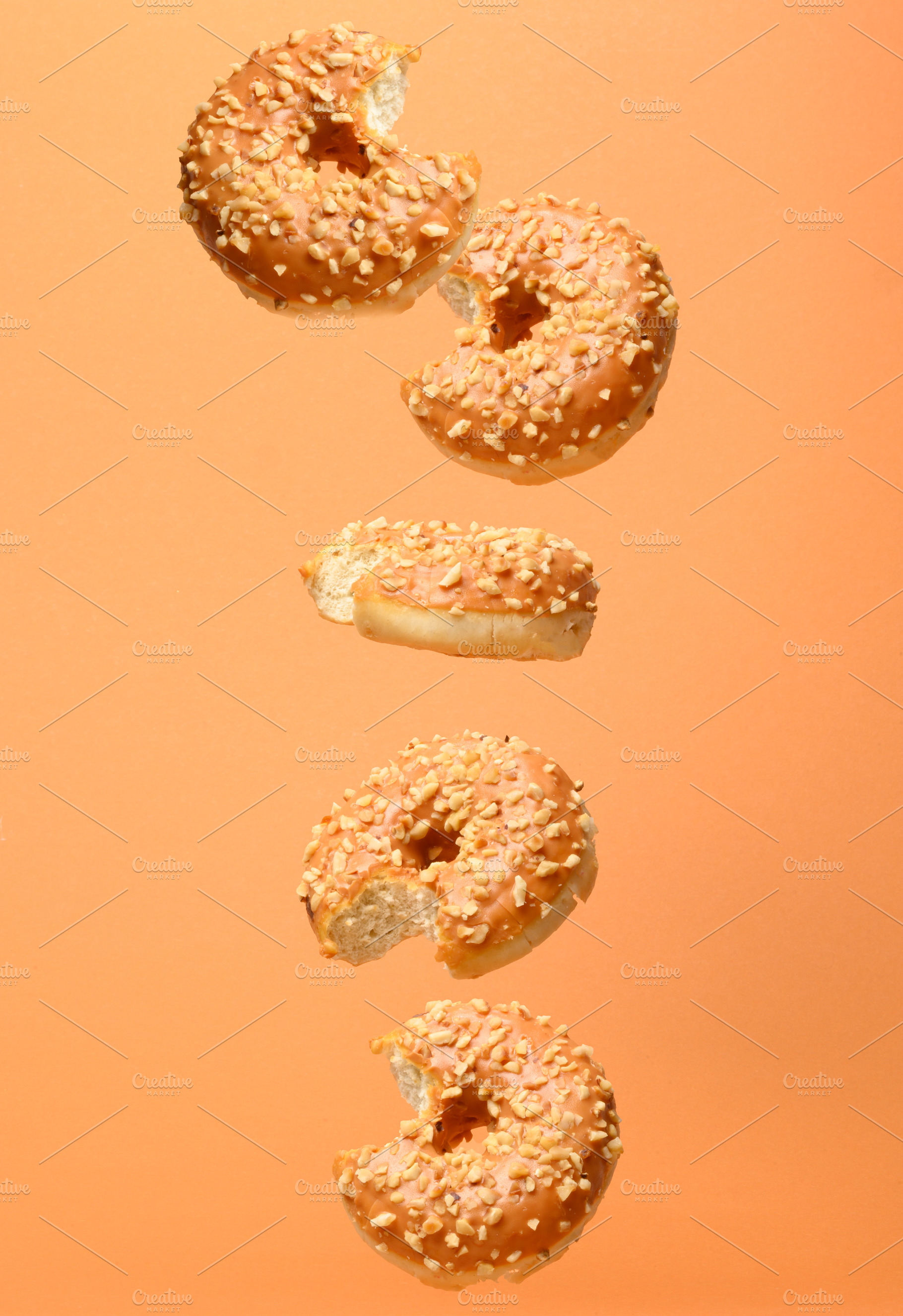 Vertical composition of levitating bitten caramel donuts with nu, a Food & Drink Photo by ndanko