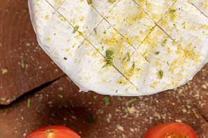 white soft cheese in salt and spices and small red round tomatoes on the table, a Photo by rsoollAI