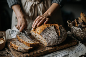 Woman slicing sourdough bread, a Person Photo by Virgo Studio