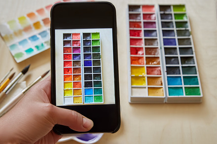 woman hand with smartphone - takes a picture of the box watercolors