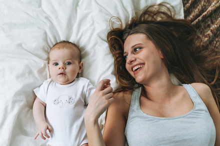 Young mother with baby girl on bed, a Person Photo by Galina_Zhigalova