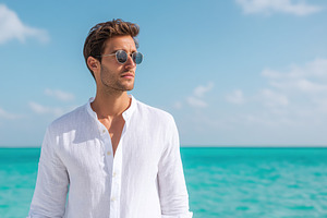 Man in white linen shirt enjoying time by the turquoise sea under a clear blue, a Person Photo by AlyaAnd