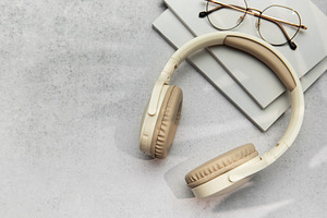 Modern wireless headphones lying on table next to books and eyeg, a Technology Photo by Olena Rudo