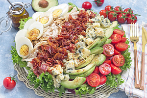 Delicious Cobb salad with greens, tomato, avocado, blue cheese, bacon, chicken, a Food & Drink Photo by iuliia_n