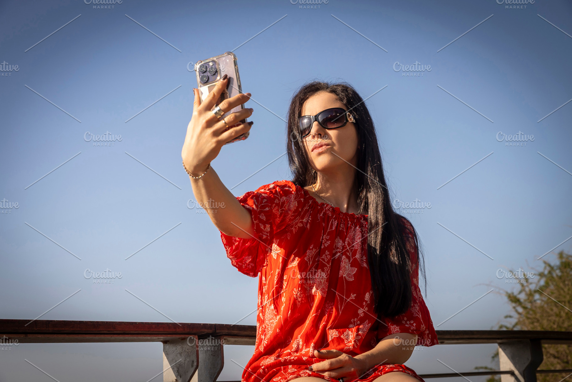 Young woman in a red off-shoulder dress and sunglasses taking a, a Person Photo by Imaginarium