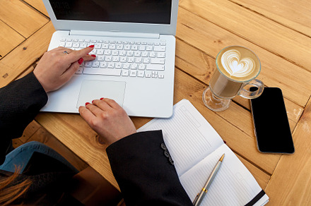 Female hands with red manicure on the background of a white laptop, a Person Photo by Photostock