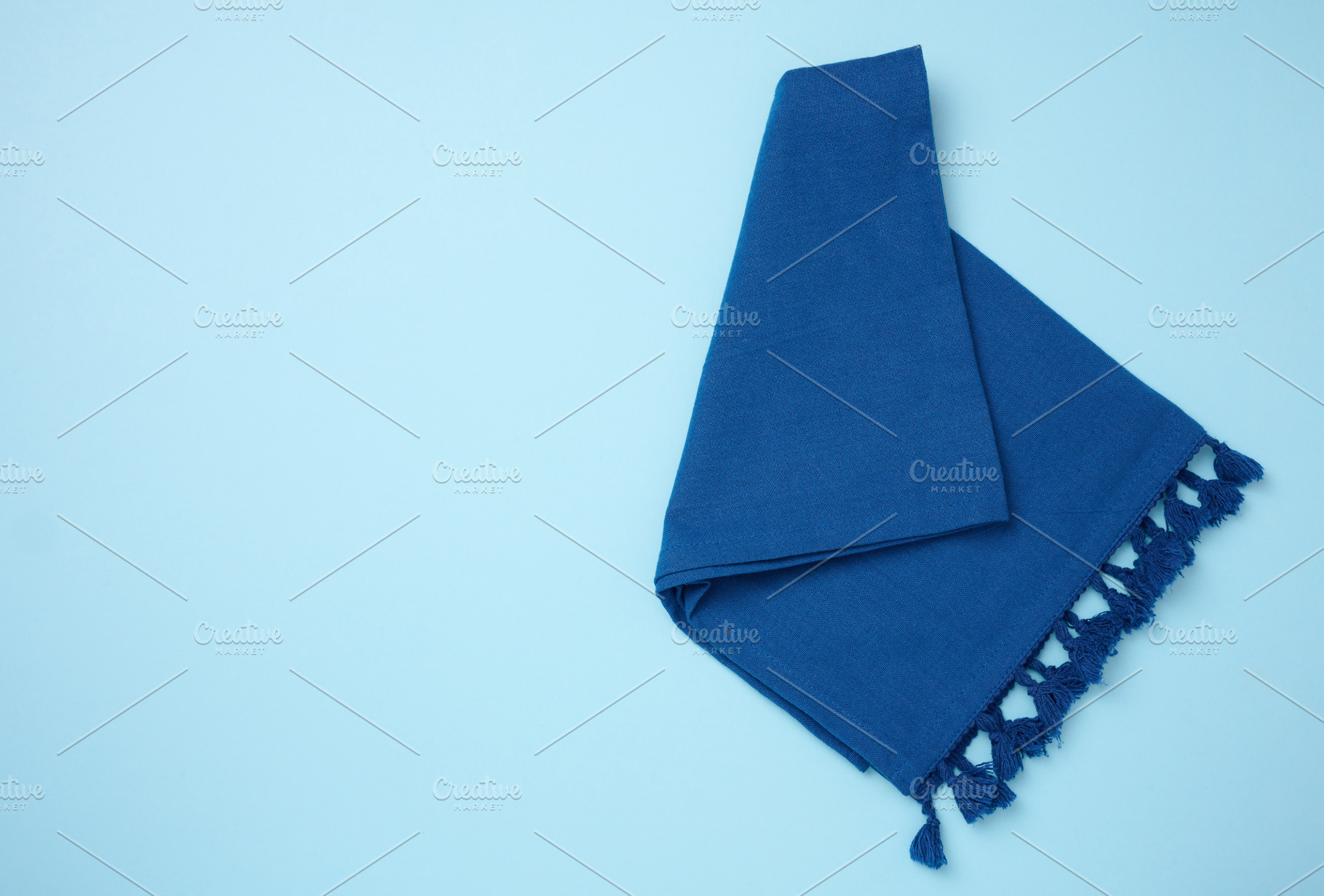 Folded blue kitchen towel on a blue background, top view. Copy s, a Food & Drink Photo by ndanko
