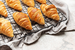 Freshly baked croissants cooling on wire rack, perfect start to, a Food & Drink Photo by Olena Rudo