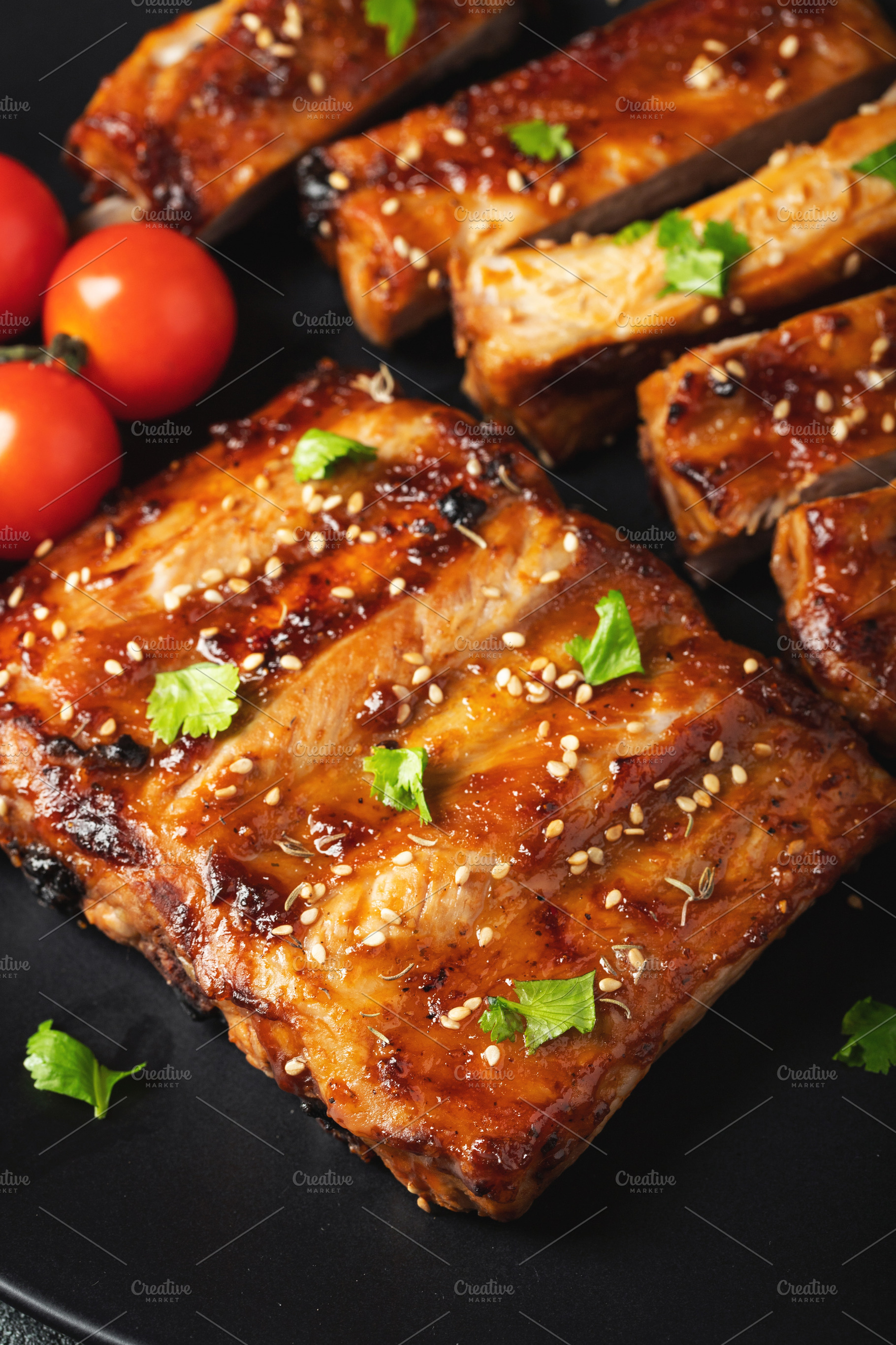 Hot grilled spare ribs from a summer BBQ served on a plate with sauce. Top view, a Food & Drink Photo by Budarinphoto