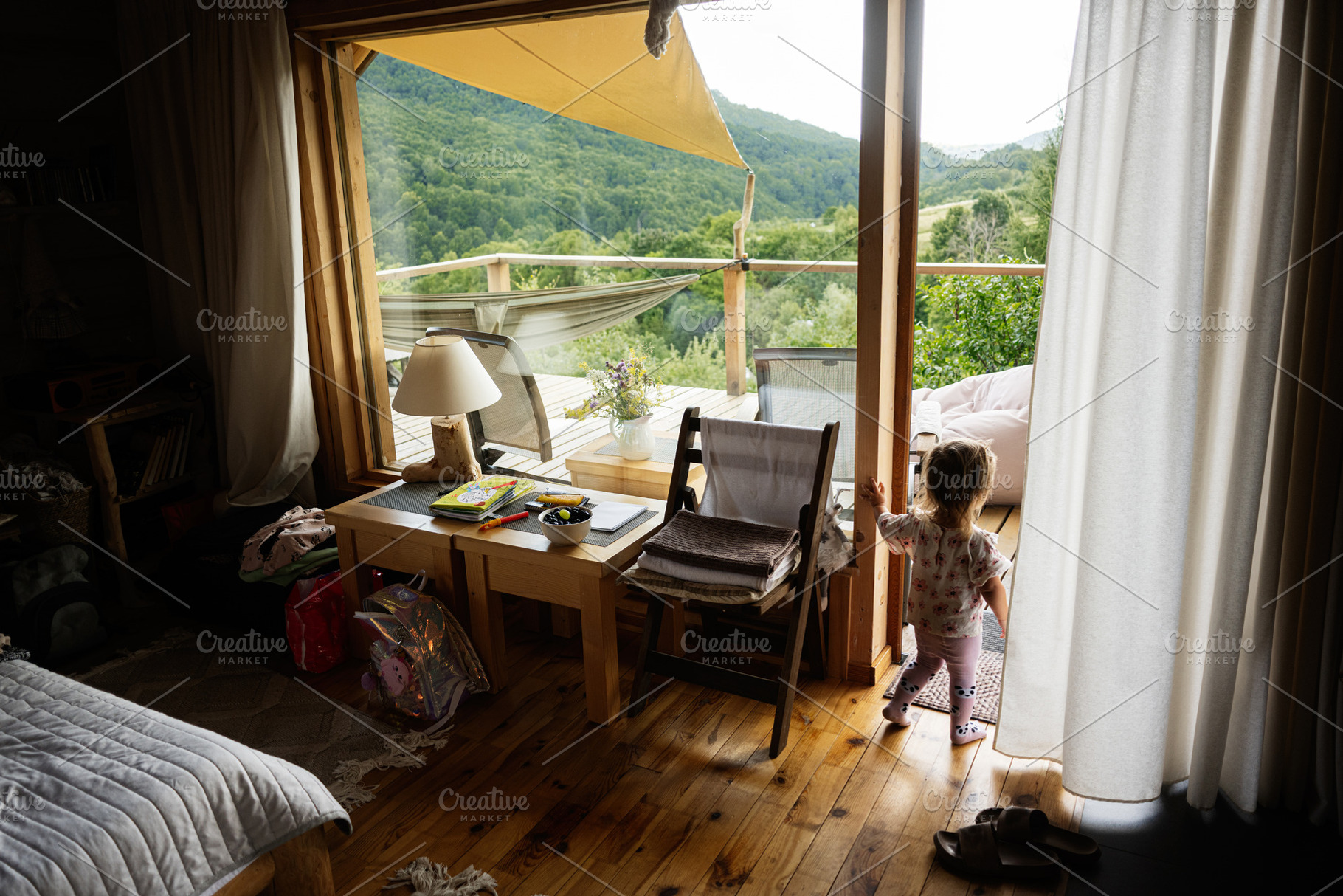 Child exploring beautiful cozy interiors with nature views from a wooden cabin, a Photo by AS photostudio