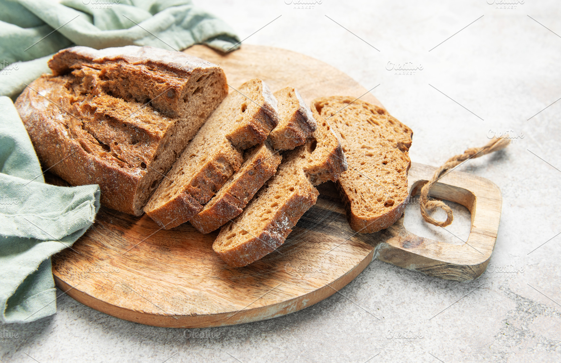 Slicing fresh whole grain rye bread on wooden board, a Food & Drink Photo by Olena Rudo
