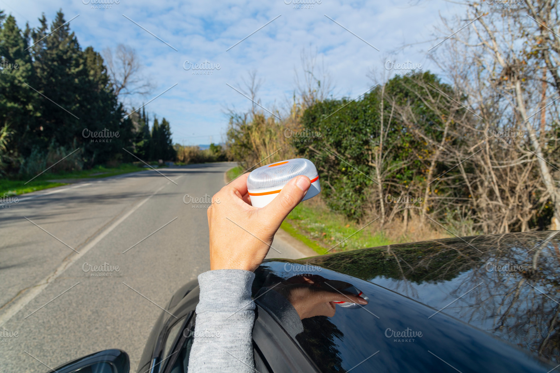 a man placing a V16 warning beacon on the car, a Photo by Nito