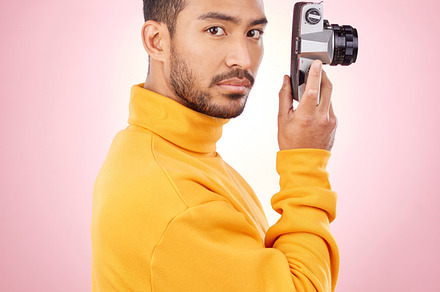 Portrait, man with a camera and creative photography or taking a picture for art, travel or record of a memory. Serious photographer, technology and shooting on retro or vintage film in studio, a Photo by Peopleimages.com