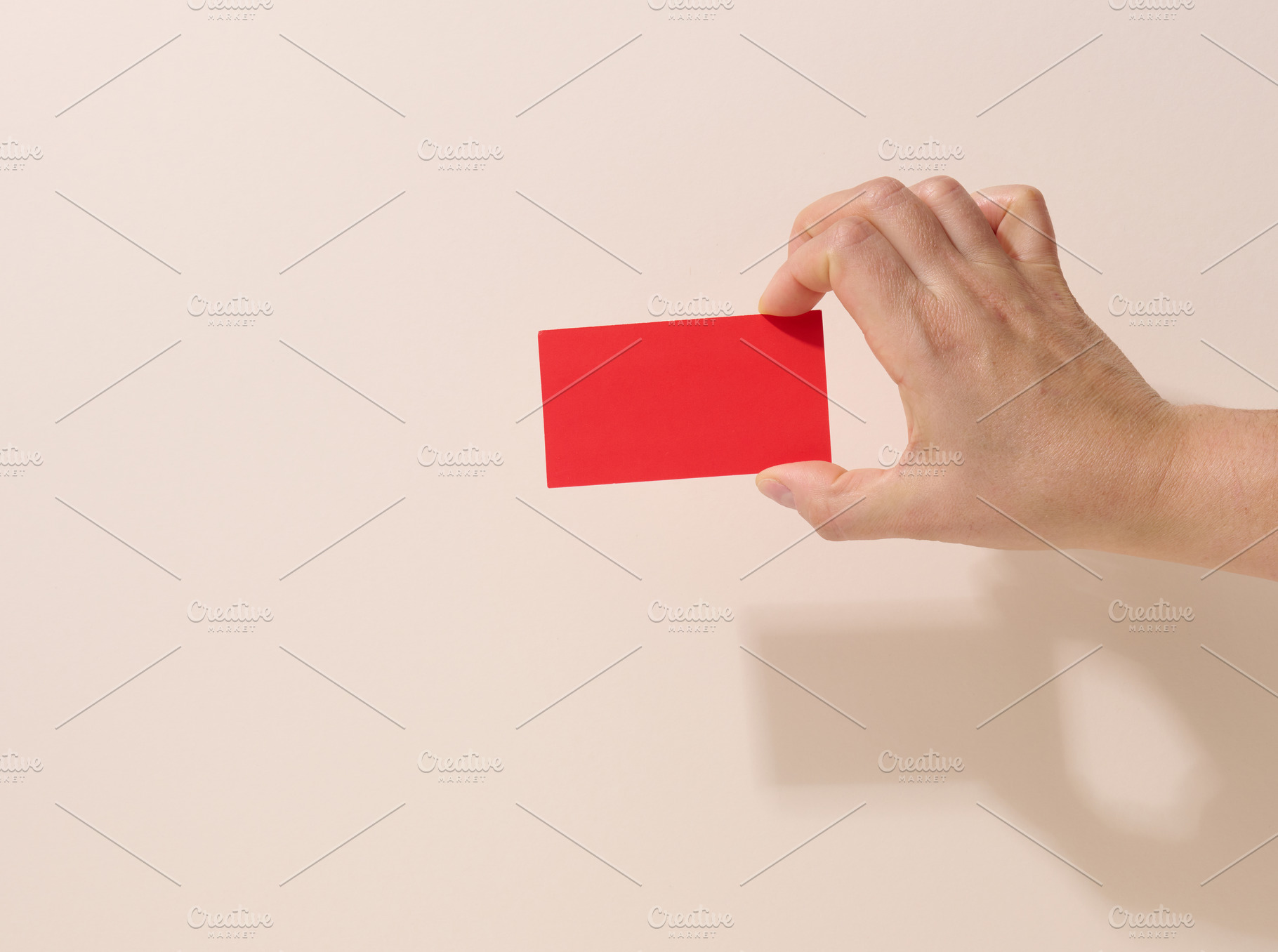 Female hand holding empty red paper on a beige background. Copy, a Business Photo by ndanko
