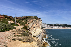 Scenic coastline view in Nazaré, Portugal with cliffs and a distant town, a Photo by AS photostudio