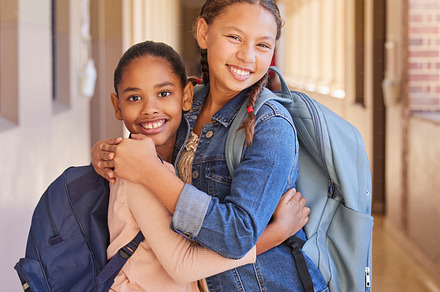 Children, school and backpack on happy students or friends excited about learning, education and making friends. Portrait of girl kids together diversity, knowledge and development in hallway, a Photo by Peopleimages.com
