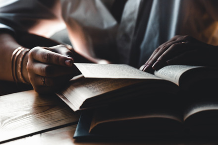 A woman is reading a book education featuring background, woman, and hand