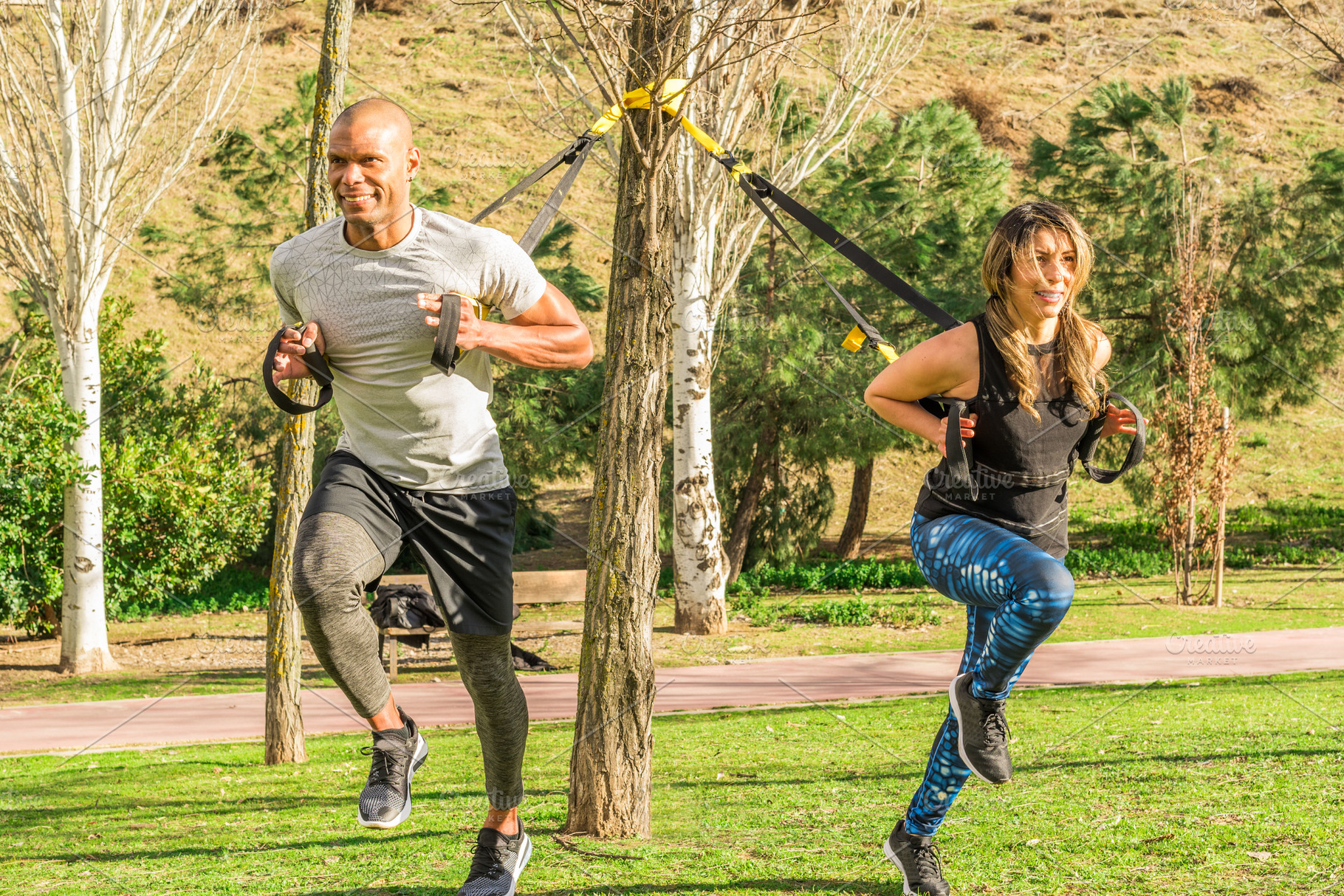 Fitness couple doing back legs exercise with trx fitness straps in park, a Sports & Recreation Photo by Iván Moreno STOCK PHOTO