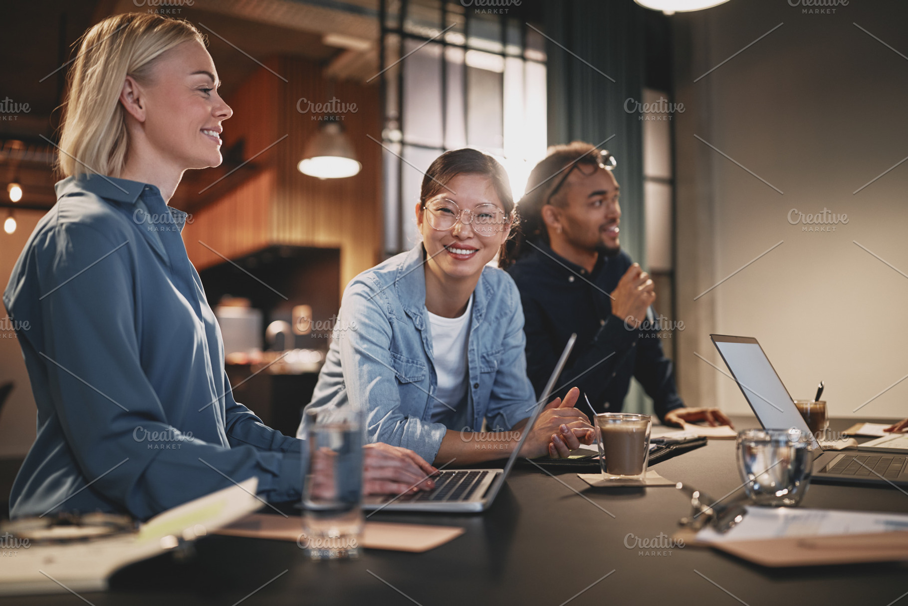 Smiling Asian businesswoman working with colleagues in an office, a Business Photo by Stefan & Janni