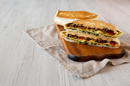 Tasty Homemade Beef Crunchwrap Quesadilla on a rustic wooden boa, a Food & Drink Photo by LiudmylaChuhunova