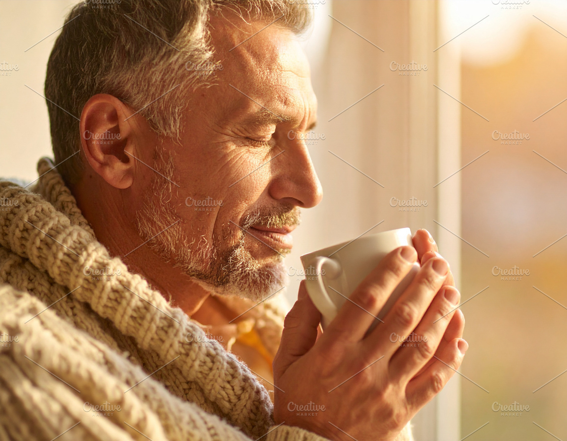 Middle-aged man with eyes closed, holding a warm cup with both h, a Health & Medical Photo by DanFLCreativo
