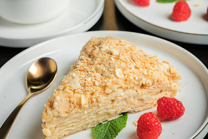 Sliced Napoleon cake on a white wooden table. Classic dessert, a Food & Drink Photo by Budarinphoto
